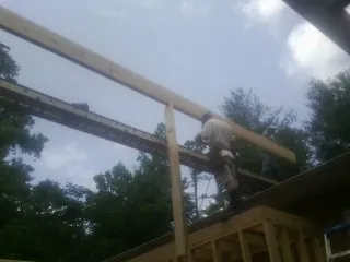 Carpenter setting a ridge beam over a new addition frame — Ice Dam Removal by Roofing Brothers in Beecher