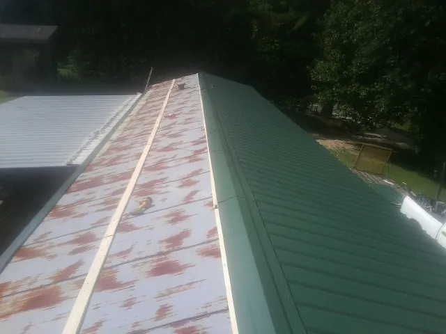 Old rusted panels beside newly installed green metal roofing — Wind Damage Roof Repair by Roofing Brothers in Beecher