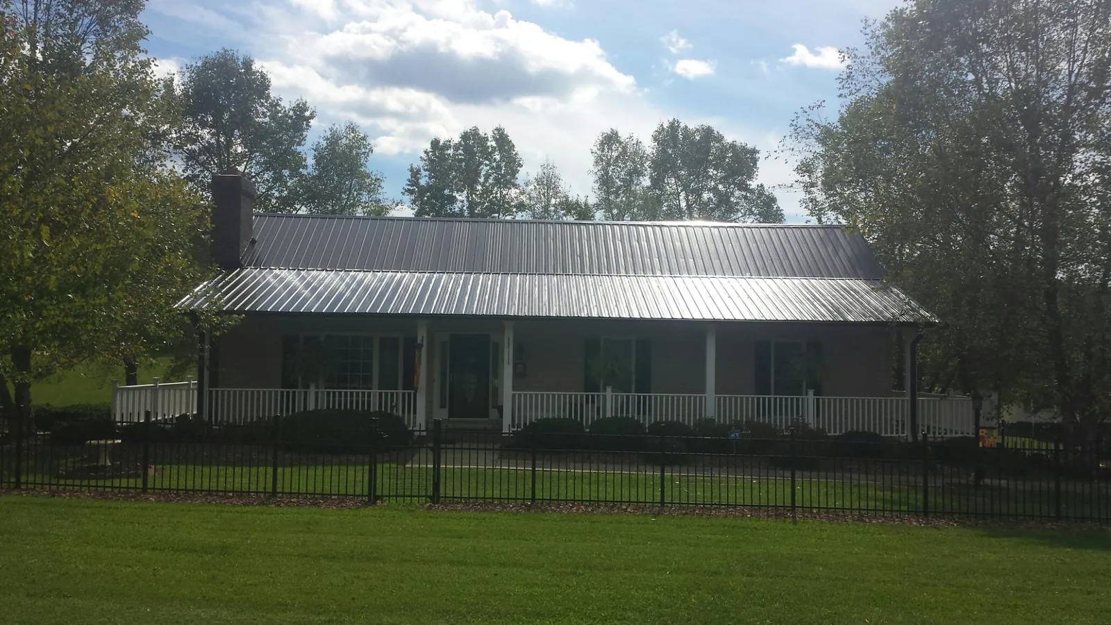 Gray metal roof on a brick ranch with a full width front porch — Gutter Guard Installation work by our crew in Beecher