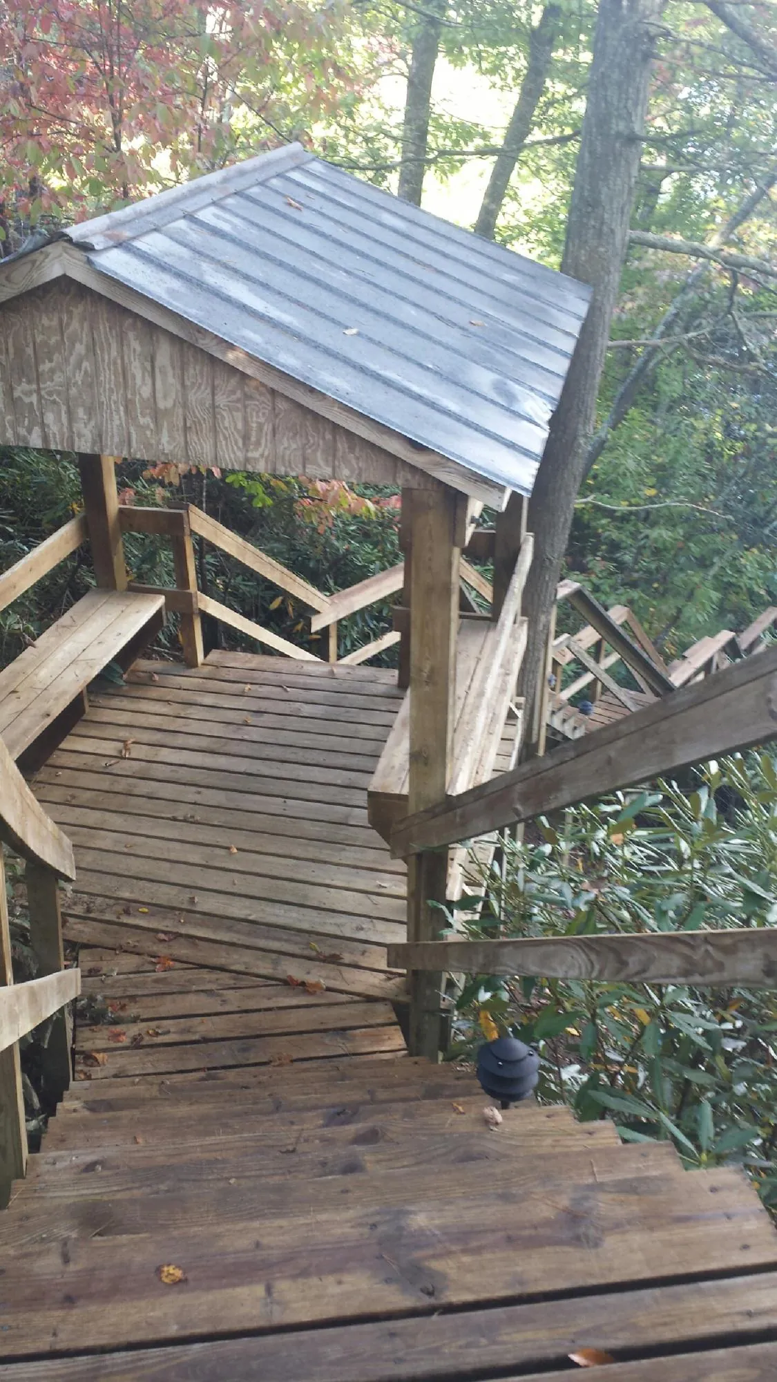 Metal roofed shelter over wooden steps on a wooded walkway — Skylight Repair & Installation work by our crew in Beecher